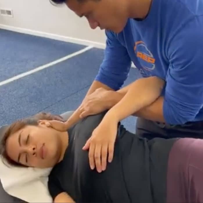 Therapist performing assisted stretch therapy on a client during a professional training session