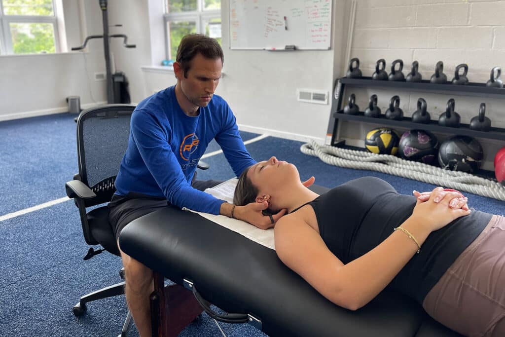 Professional stretch therapist performing assisted neck stretch on client in a clinic setting