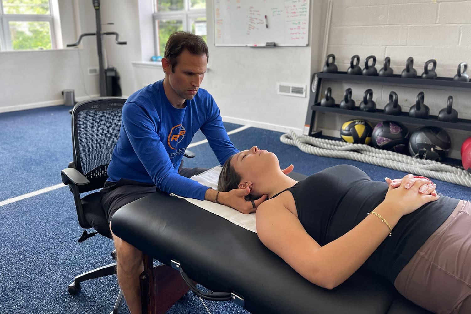 Professional stretch therapist performing assisted neck stretch on client in a clinic setting